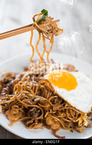 Char kway teow sauté de crevettes et de chopstick sur fond de bois. Banque D'Images