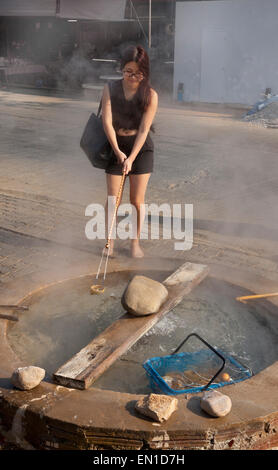 Les sources d'eau chaude à Wieng Pa Pao, Chiang Rai, Thaïlande du Nord. Jeune femme faisant bouillir les oeufs dans l'eau chaude Banque D'Images