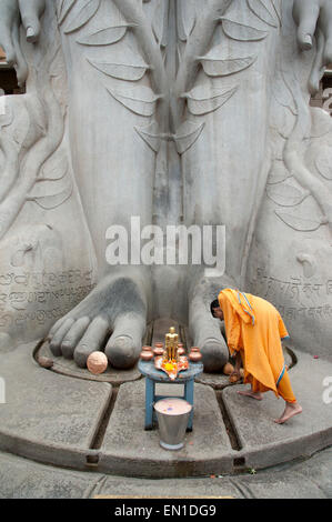 (Gommateshwara Bahubali) Jain temple en Inde. Pieds de 17 mètres statue de Bahubali monolithique. Prêtre offrant des prières. Banque D'Images