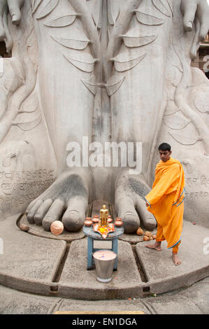 (Gommateshwara Bahubali) Jain temple en Inde. Pieds de 17 mètres statue de Bahubali monolithique. Prêtre offrant des prières. Banque D'Images