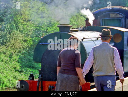 L'homme et la femme attraper porter train à vapeur des années 1940, années 1950, années 1930, vêtements, avec un chapeau et canne à sucre Banque D'Images