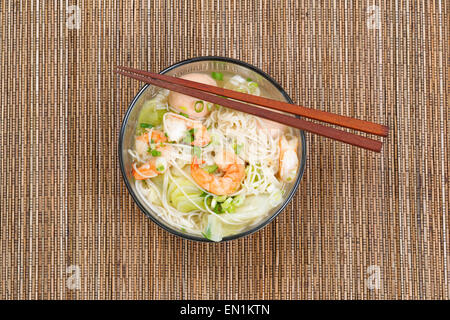 Haut voir l'image de la soupe de nouilles chinoises dans un bol en verre clair sur le haut de la place bambou naturel mat. La mise en page en format horizontal. Banque D'Images