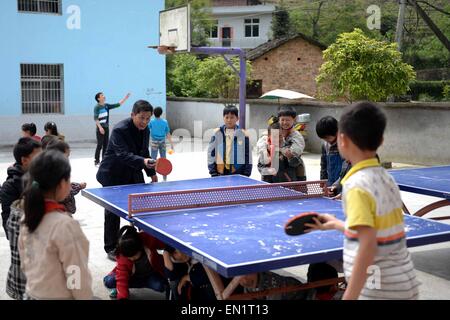 Luxi, province de Jiangxi en Chine. Apr 24, 2015. Dayong Wang joue au tennis de table, tandis que son fils Wang Dechang joue au basket-ball avec les élèves de l'école primaire de Village Zaxi Zhangjiafang Ville de Luxi, comté de la Province de Chine orientale, le 24 avril 2015. Le 56-year-old Wang Dayong et son 28-année-vieux fils ont enseigné dans cette école rurale, qui est situé en zone de montagne, pour 36 ans et 10 ans respectivement. © Chen Zixia/Xinhua/Alamy Live News Banque D'Images