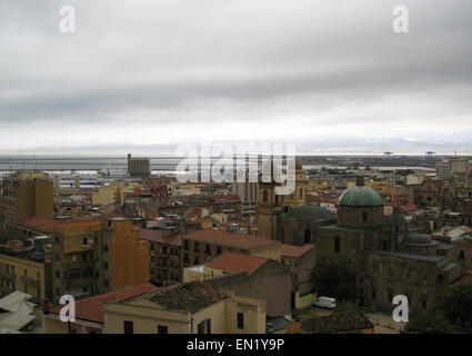 L'horizon de Cagliari avec bâtiments, port, mer et ciel nuageux gris sombre en Sardaigne Banque D'Images