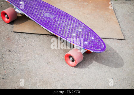 Petite taille en plastique violet moderne skateboard, repose sur une chaussée urbaine d'asphalte Banque D'Images