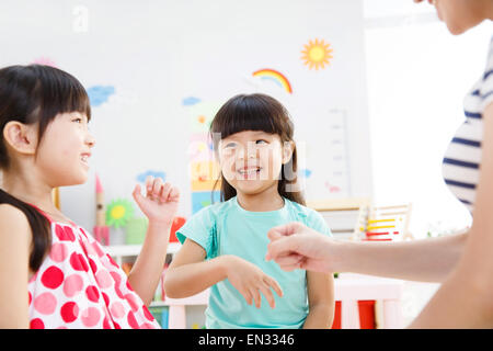 L'enseignant de maternelle et la jeune fille dans le jeu de devinettes doigt Banque D'Images