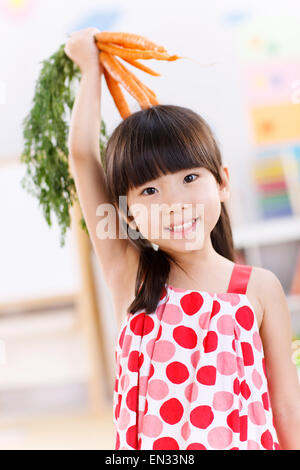 Cute little girl holding carrots Banque D'Images