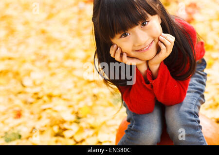 Belle petite fille assise sur la citrouille Banque D'Images