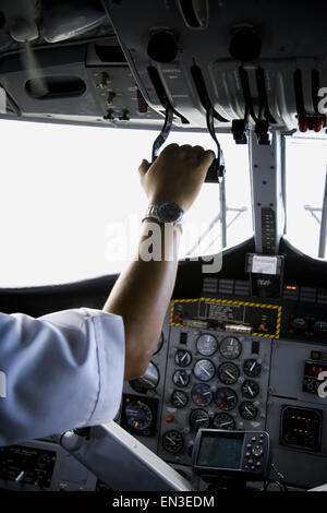 Vue arrière d'un pilote actionnant le panneau de contrôle dans un avion Banque D'Images