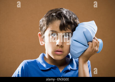 Boy holding ice pack à la tête Banque D'Images