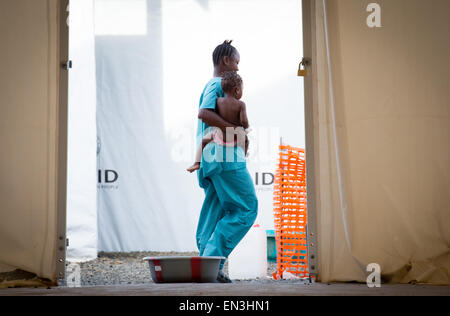 Monrovia, Libéria. Apr 9, 2015. Un adjoint médical porte une petite fille malade dans sa nuit dans un hôpital du SITTU (infection grave de l'unité de traitement temporaire) à Monrovia, Libéria, 9 avril 2015. Photo : Kay Nietfeld/dpa/Alamy Live News Banque D'Images