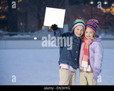 Deux jeunes filles à l'extérieur en hiver avec blank sign Banque D'Images