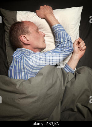 L'homme en pyjamas ou pyjama sleeping in bed Banque D'Images