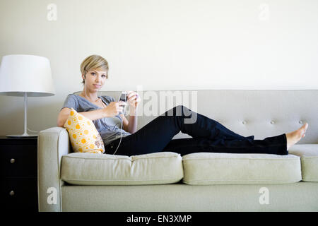 Femme assise sur la table de l'écoute d'un iPod Banque D'Images