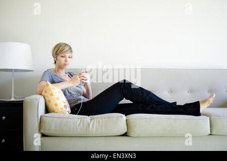 Femme assise sur la table de l'écoute d'un iPod Banque D'Images