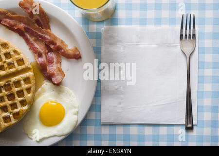 Bacon et d'oeufs à la gaufre et de jus d'orange avec la fourchette et serviette Banque D'Images