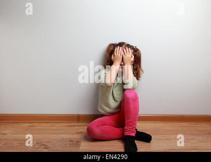 Malheureux enfant pleurer fille assise sur le sol avec la face fermée avec copie espace vide Banque D'Images