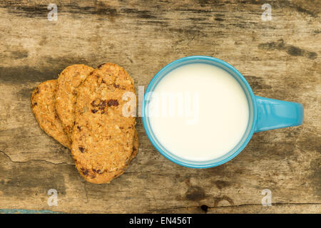 Blue tasse de lait avec des biscuits pour le petit-déjeuner sain sur table en bois Banque D'Images