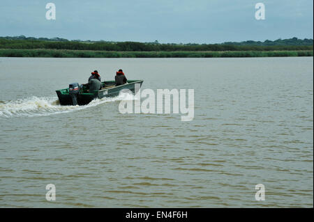 Trois hommes adultes dans la croisière en bateau sur l'ouverture de l'eau brune de iSimangoliso site du patrimoine mondial, Kwazulu-Natal, Afrique du Sud Banque D'Images