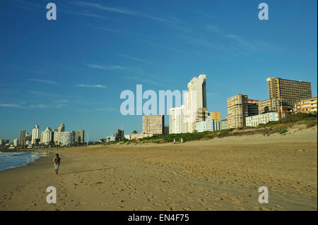 Skyline de Durban sur les quais où des profils homme prend un matin tôt jolie ballade le long de la plage de la batterie, le KwaZulu-Natal, Afrique du Sud Banque D'Images