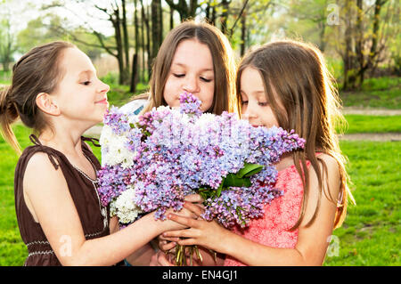 Trois filles smelling bouquet lilas ensemble Banque D'Images