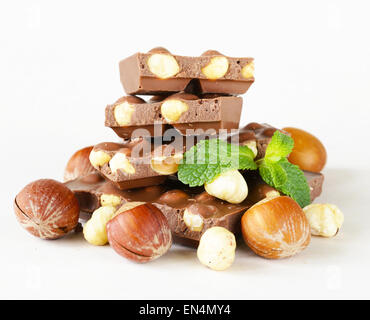 Barre de chocolat aux noisettes et de feuilles de menthe sur fond blanc Banque D'Images