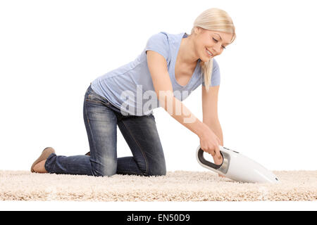 Jeune femme blonde le nettoyage d'un tapis avec un aspirateur portable isolé sur fond blanc Banque D'Images