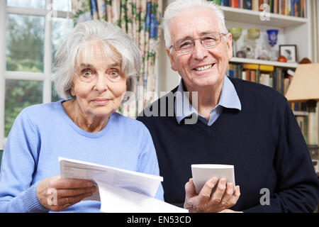 Portrait Of Smiling Senior couple l'examen des finances du foyer Banque D'Images