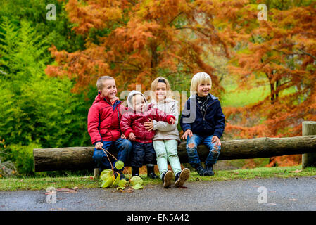 Trois garçons et une fille assis ensemble dans autumn park Banque D'Images