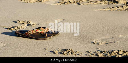 Chaussons sur une plage de sable au coucher du soleil Banque D'Images