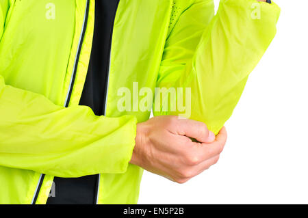 Closeup of a young caucasian sportsman portant des vêtements de sport avec sa main dans son coude à cause de sa douleur du coude Banque D'Images