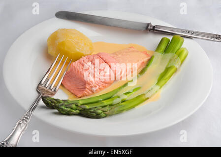 Les asperges vertes et le saumon poché avec sauce maltaise sauce hollandaise (variation) avec une pomme de terre sur une plaque blanche Banque D'Images