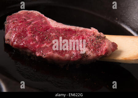 Série : Contre-filet de cuisson en poêle en fonte : Steak à la poêle avec sel et poivre étant renversé Banque D'Images