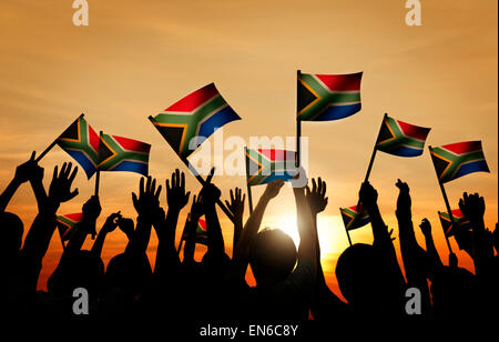 Groupe de personnes brandissant des drapeaux de l'Afrique du Sud à l'arrière allumé Banque D'Images