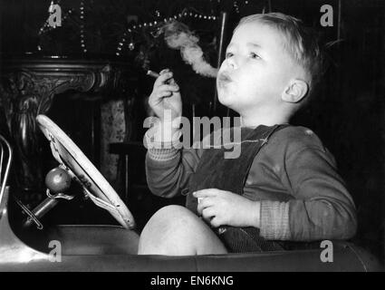 Trois ans David Fellows, inhalations loin heureux dans sa voiture à pédales, sur un homme grand cigare. M. Fellows, qui a quatre autres enfants, permet à David de fumer parce qu'elle croit que s'il est laissé à lui-même qu'il va perdre l'habitude de lui-même. Décembre 1959 Banque D'Images