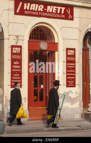 Les juifs orthodoxes en passant par une boutique de barbier dans le quartier juif de Budapest, Hongrie Banque D'Images