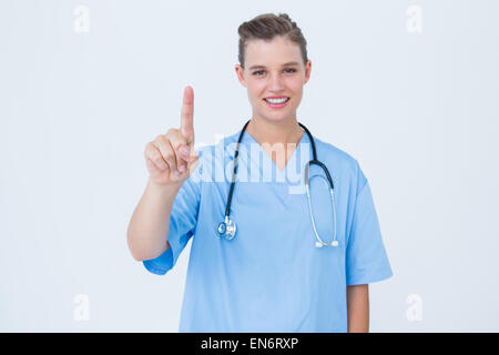 Smiling nurse pointant quelque chose Banque D'Images