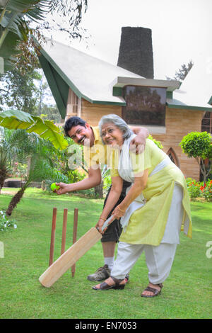 Senior woman jouer au cricket avec son fils Banque D'Images