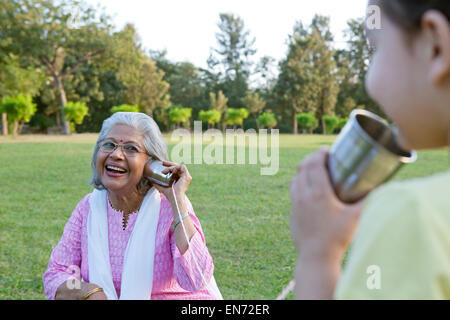 Grand-mère et petite-fille parler à travers les boîtes de conserve Banque D'Images