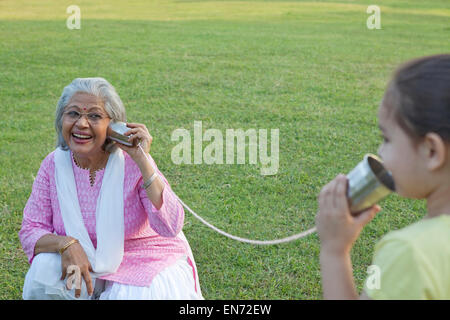 Grand-mère et petite-fille parler à travers les boîtes de conserve Banque D'Images