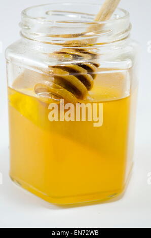 Pot de miel avec un balancier à l'intérieur sur fond blanc Banque D'Images