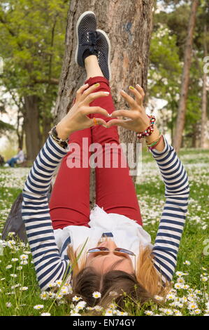 Fille brune allongé dans l'herbe pleine de fleurs Banque D'Images