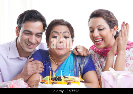 Woman blowing out candles sur un gâteau d'anniversaire Banque D'Images