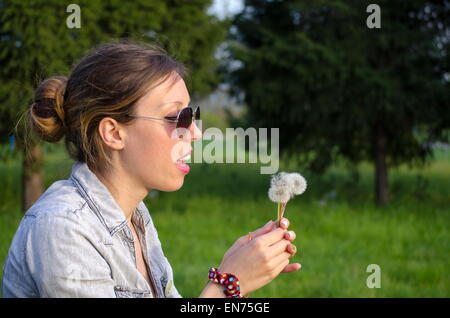 Brunette girl blowing un pissenlit Banque D'Images