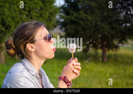 Brunette girl blowing un pissenlit Banque D'Images