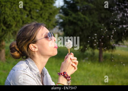 Brunette girl blowing un pissenlit Banque D'Images