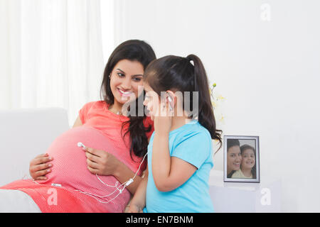Femme enceinte mise sur le ventre de l'écouteur Banque D'Images