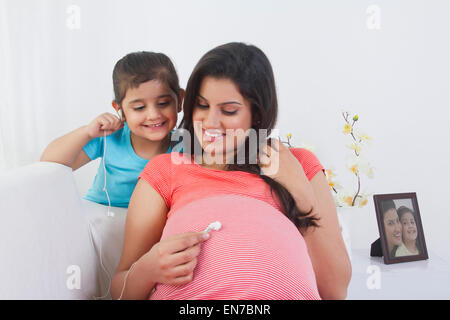 Femme enceinte mise sur le ventre de l'écouteur Banque D'Images