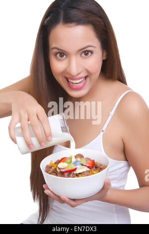 Portrait of woman pouring lait dans un bol de céréales Banque D'Images