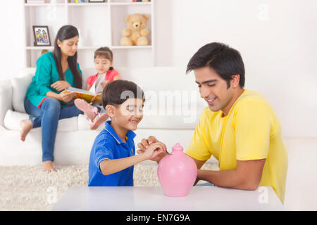 Boy putting coins in piggy bank Banque D'Images